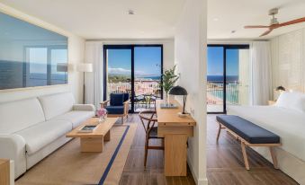 a modern living room with a large window and sliding glass door leading to an ocean view at H10 Imperial Tarraco