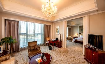 A spacious and elegantly furnished room with a bed, desk, and chair in the center at Grand Metropark Guofeng Hotel, Tangshan