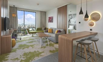 In the middle of the living room, there are large windows and furniture, including an area rug at Holiday Inn & Suites Saigon Airport