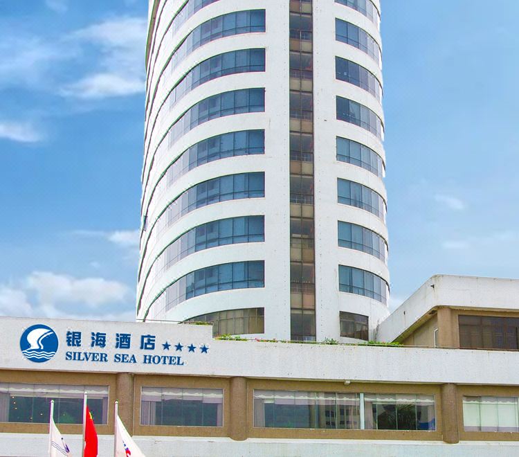a tall white building with a curved facade , possibly a hotel or an office building at Silver Sea Hotel
