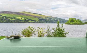 a ping pong table set up on a grassy field near a body of water , possibly a lake at The Kenmore Club