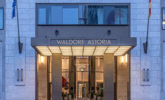 the entrance of the waldorf astoria hotel , with its name displayed above the door and several potted plants on either side at Waldorf Astoria Berlin