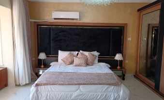 a large bed with white linens and a black headboard is situated in a bedroom with a chandelier at Indiana Hotel
