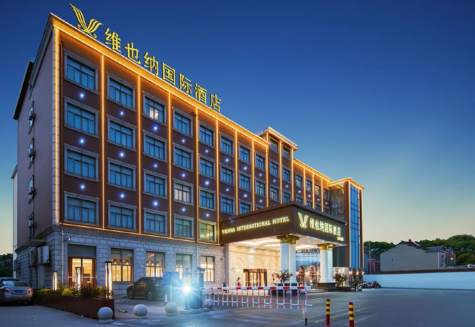 The large white and blue building in the background creates an impressive front view at night at Vienna International Hotel (Shanghai Pudong Airport)
