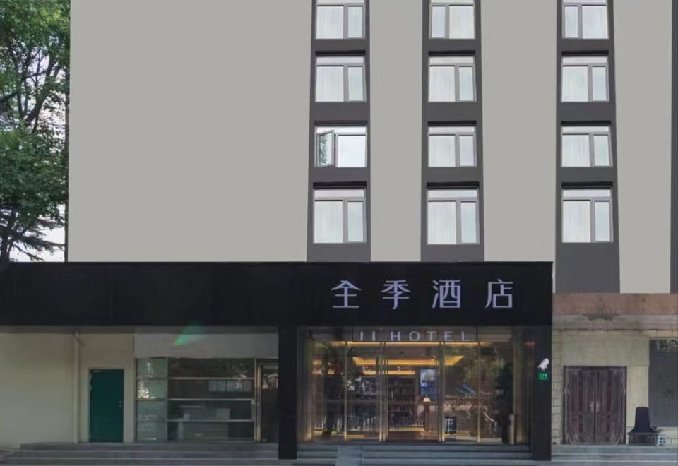 The front entrance of a hotel is depicted, featuring a sign above it and an illuminated doorway at Ji Hotel (Shanghai Hongqiao Shuicheng Road)