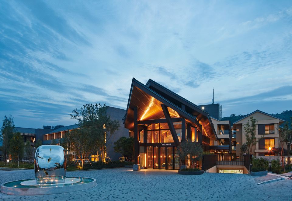 The exterior view at night shows a large building in front with an illuminated roof at The Westin Yilan Resort