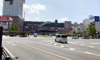 a busy city street with multiple vehicles , including cars , buses , and a truck , driving down the road at Toyoko Inn Oita Ekimae
