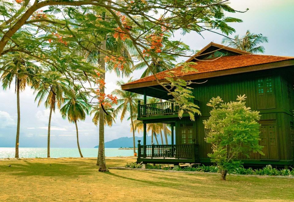 a wooden house surrounded by palm trees and a body of water , creating a picturesque scene at Pelangi Beach Resort & Spa, Langkawi