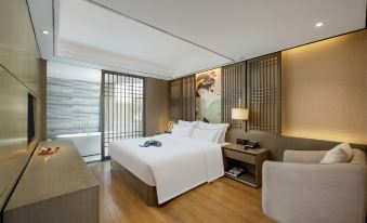 a modern hotel room with a large bed , white bedding , and a wooden floor , as well as a bathroom with a bathtub and a sink at Mianyang Booking Hotel