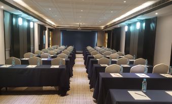 a large conference room with rows of tables and chairs , blue tablecloths , and a screen at GuiLin ParkView Hotel