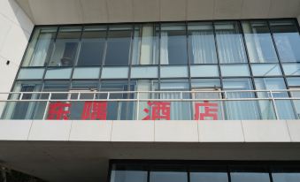 a building with a large glass window and a balcony with red chinese characters on it at Dongji Island Dongguan Hotel