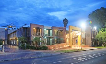 a modern building with multiple floors , lit by street lamps at night , and a palm tree nearby at Stay at Alice Springs Hotel