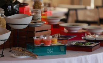 A table is set with plates, bowls, and glasses filled with food for serving at UrCove by HYATT Beijing Forbidden City