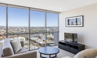 a living room with a large window overlooking the city , featuring a couch , television , and coffee table at The Milton Brisbane