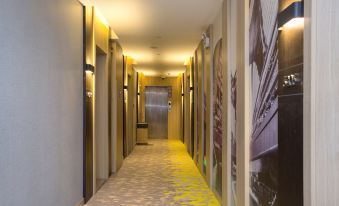A long hallway with yellow walls and tiled floors leads to doors on both sides at Jimu Xiaozhu Hotel (Shanghai Jing'an Temple)