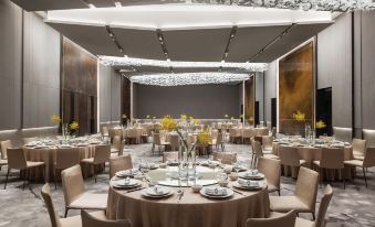 A spacious room is set up with round tables and chairs for an event or formal dining at Cordis Shanghai Hongqiao