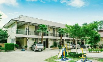 a large white building with a balcony and palm trees , surrounded by a parking lot with cars at Palm Sweet Resort