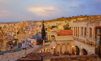 a picturesque town with old buildings , stone streets , and mountains , bathed in the warm glow of sunset at Sultan Cave Suites