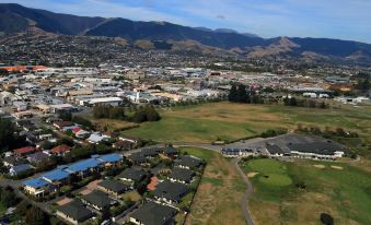 aerial view of a small town surrounded by mountains , with a golf course in the foreground at Greens Motel