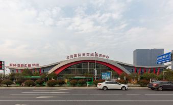 There is a large building with cars parked in front and an entrance to the main road at Yiwu Mankalan Hotel (International Trade City Xinguanghui Branch)