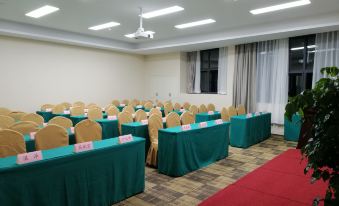 A spacious event room is arranged with long tables and green chairs positioned towards the front at Chunguang Hotel