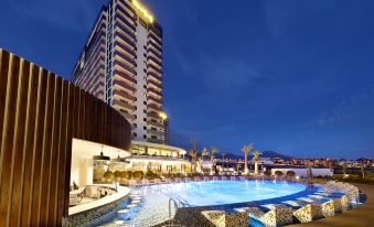 a large hotel with a swimming pool in the foreground , surrounded by trees and buildings at Hard Rock Hotel Tenerife