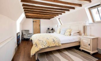 a spacious bedroom with a king - sized bed , hardwood floors , and a television mounted on the wall at The Lamb at Angmering
