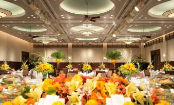 a well - decorated banquet hall with a round ceiling , large flower arrangements , and tables set for dining at Oriental Hotel Tokyo Bay