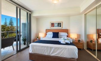 a bedroom with a large bed , two lamps , and a sliding glass door leading to a balcony at Scarborough Beach Resort