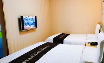 The room is empty and white, with two beds and a TV mounted on the wall in front at 7 Days Inn (Beijing Temple of Heaven Dongmen Metro Station)