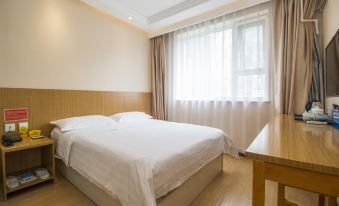 The bedroom features white sheets, a wooden bed, a large window in the middle on one side, and a small table with a lamp on the other side at Ruizhao Hotel (Beijing Guomao)