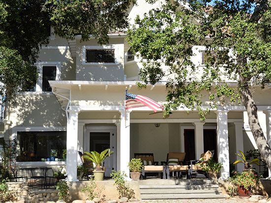 a white house with a flag flying in front of it , surrounded by trees and benches at Arroyo Vista Inn