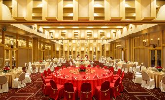 A spacious ballroom is elegantly arranged with red chairs and tables, ready for an event or formal dining at Regency Art Hotel