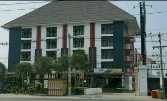 a modern building with a red and white exterior , surrounded by trees and parked cars at Thanarom Place