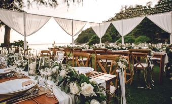 a wedding reception on the beach , with tables set up for guests and decorated with flowers at The Naka Phuket