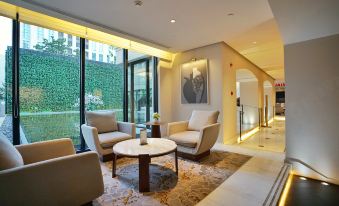 elegant and spacious living area, complete with ample natural light from the large windows, and tastefully arranged with comfortable chairs and tables at Jinjiang Metropolo Classiq Jing'An Hotel