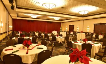 a large , well - decorated banquet hall with multiple tables set for a formal event , including white tablecloths , red napkins , at Radisson Hotel Niagara Falls Grand Island