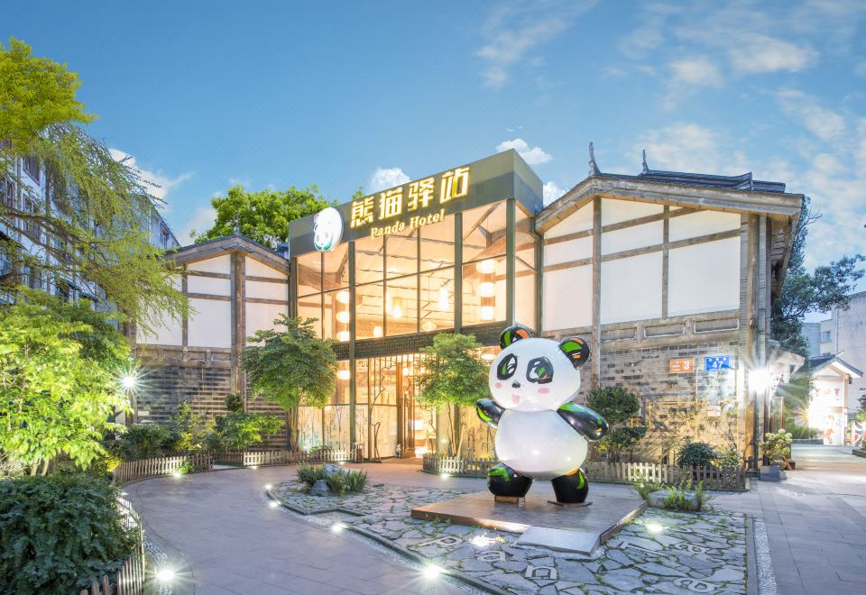 a large panda statue is in front of a building with chinese characters on it at Panda Hotel