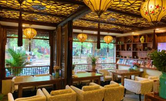 There is a restaurant featuring large windows, tables in the middle, and an open doorway at Zhouzhuang Latte Play Stone Mulan Hotel