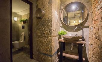 a bathroom with stone walls , a wooden sink , and a mirror , as well as a toilet and bathtub at Z Hotel