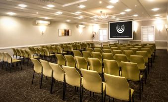 a large conference room with rows of yellow chairs arranged in front of a projector screen at Gold Reef City Theme Park Hotel