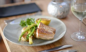 a plate of food with a piece of meat , asparagus , and other vegetables is on a table at Berry Village Boutique Motel