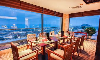 a restaurant with large windows offering a view of the city , and several tables set for dining at Sai Gon Ha Long Hotel
