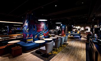 a modern lounge area with blue and black chairs , couches , and a unique mural on the wall at Just Sleep Ximending