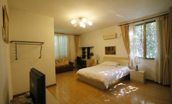 A bedroom with hardwood floors and large windows is illuminated by a central small bed at Beehome  Hostel