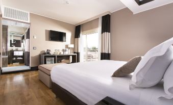 a large bed with a white blanket is in a room with wooden floors and a television mounted on the wall at Rome Times Hotel