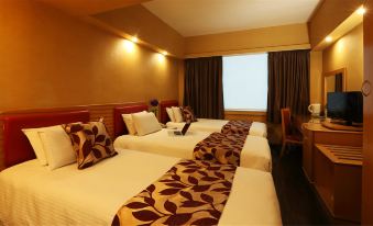 The bedroom is empty and features two beds and a large window on the side at Imperial Hotel