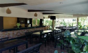 a restaurant with multiple dining tables and chairs , as well as a bar area with several potted plants at Palm Sweet Resort