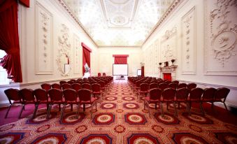 a large , elegant room with a red carpet and white walls , featuring rows of chairs arranged in a symmetrical pattern at Lumley Castle Hotel