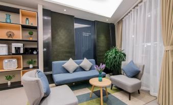 In the living room, there is a sofa, chair, and table positioned in the center near a small window at Home Inn Selected (South Square of Shanghai Railway Station)